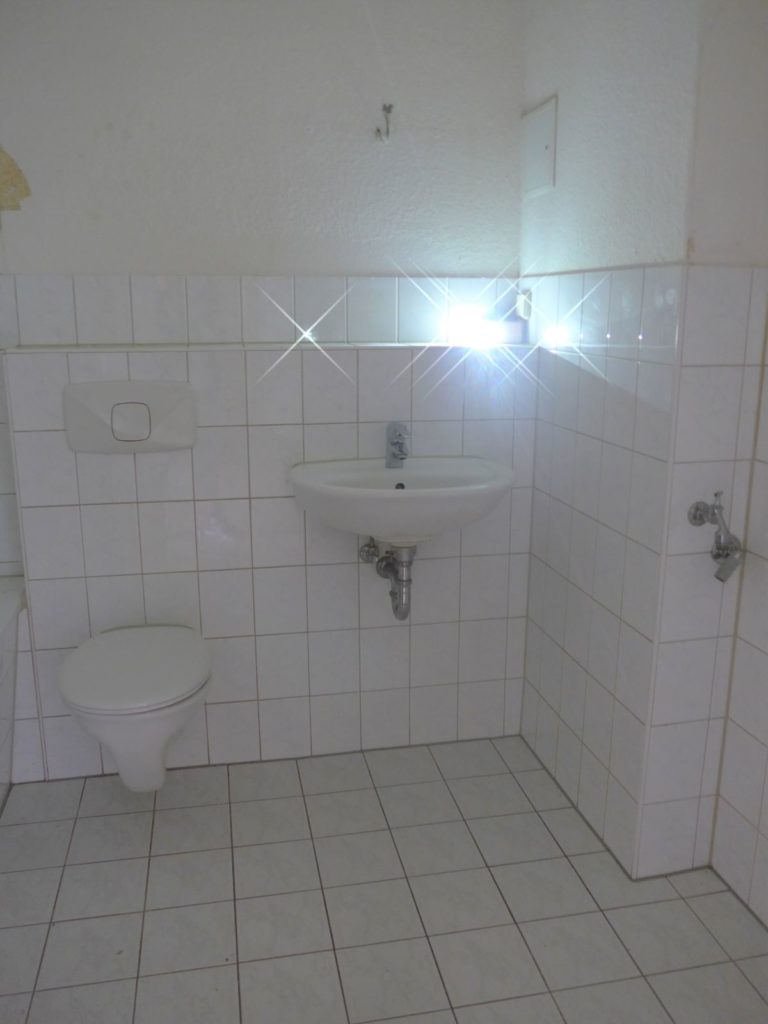 innenliegendes Bad, ohne Fenster, helle Fliesen, Badewanne, Waschbecken und WC