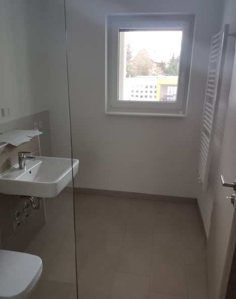 Feistkornstraße 9a 7 Helles Tageslichtbad mit beigen Bodenfliesen und weißen Wänden, Waschbecken, WC und Waschmaschinenanschluss