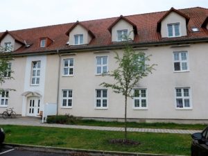 Außenansicht Haus, mit Grünalage und Sitzbank vor dem EIngang